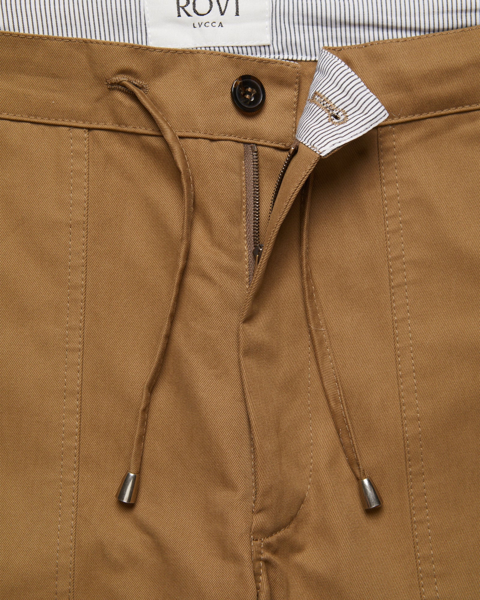 Close-up of Garden Pants in Drab cotton twill showing drawstring waist, signature ticking lining, and button-zip closure.