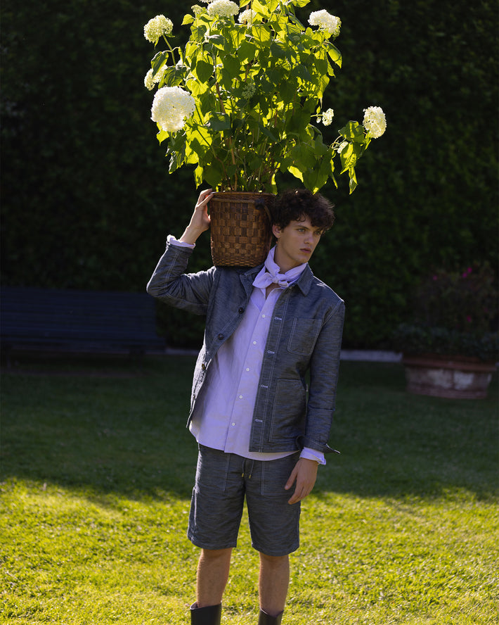 Rovi Lucca SS24 – Palazzo Pfanner: Garden jacket in navy denim ‘filaticco’, paired with a lilac cotton oxford garden shirt and navy denim garden shorts.