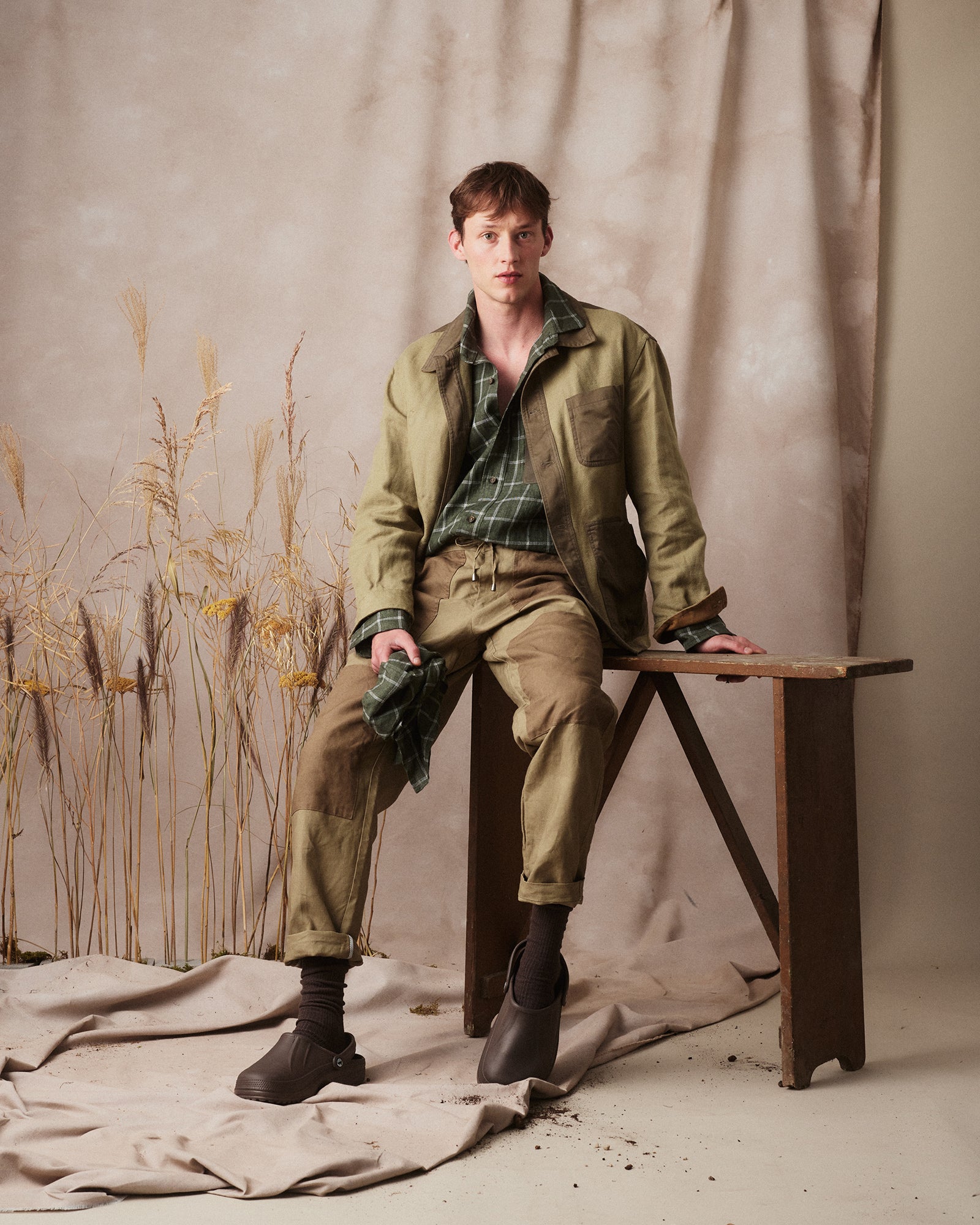 Rovi Lucca FW24 Herbarium – garden jacket in verde linen canvas and cotton drill with contrasting lovat and khaki details, utility pockets, and drawstring waist, paired with a green checked linen shirt with cotton drill patch pocket, and garden pants in sage and rope linen with utility pockets, knee patch, button/zip closure, and adjustable drawstring waist.