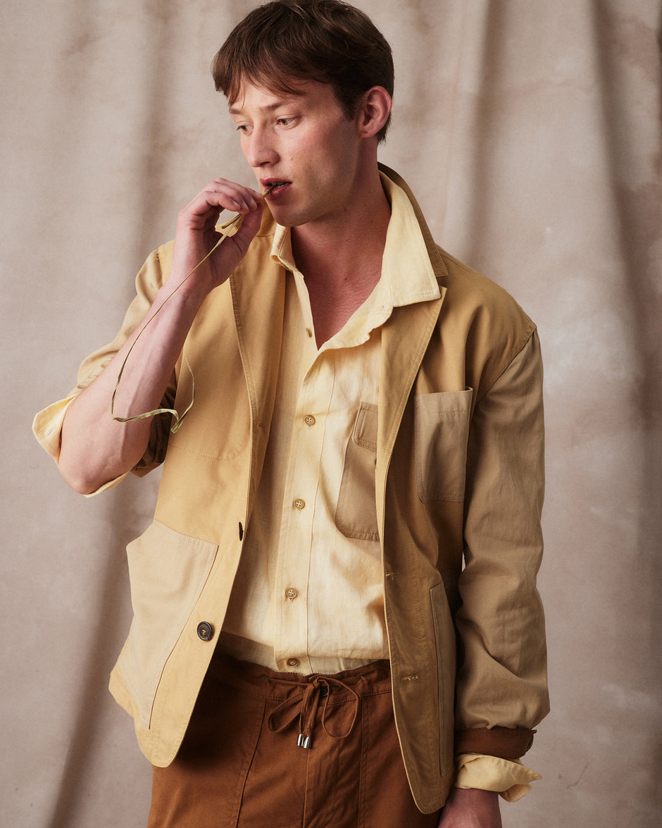 Rovi Lucca FW24 Herbarium – garden blazer in beige cotton drill with contrasting putty and tobacco details, utility pockets, and drawstring waist, paired with a wheat linen shirt with cotton drill patch pocket, and garden pants in tobacco cotton drill with utility pockets, knee patch, button/zip closure, and drawstring waist.